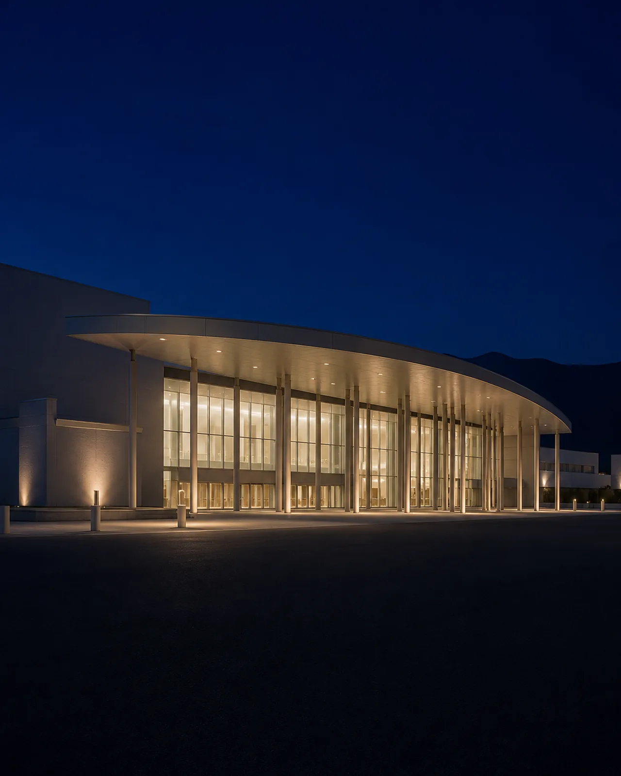 The sweeping curved entrance canopy and glass facade of Ontario Convention Center glow at blue hour.