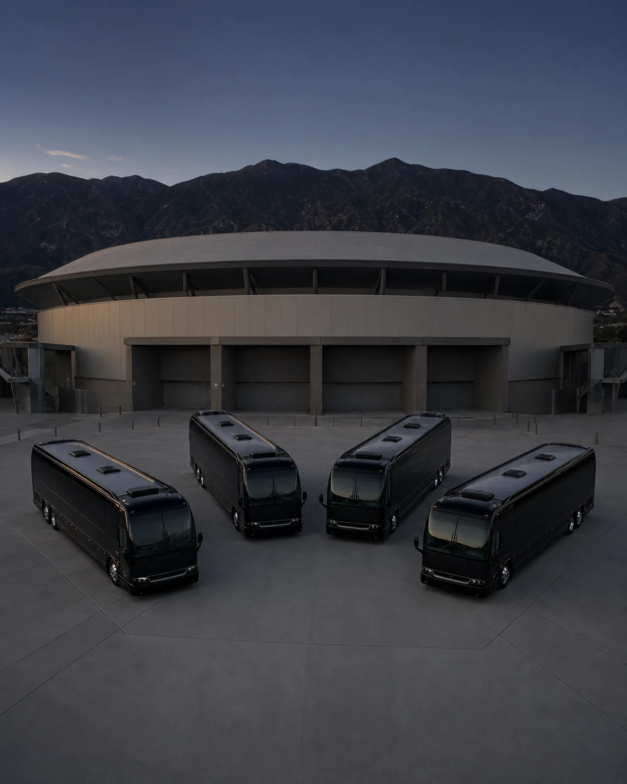 Four near-black full-size motorcoaches form a broad arc outside Toyota Arena in Ontario.